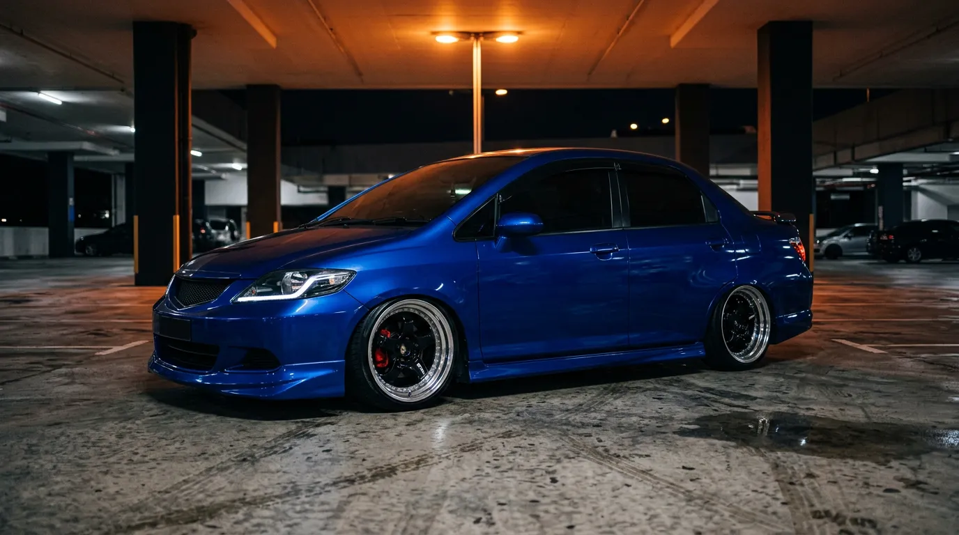 A candy blue Honda City build slammed on deep-dish wheels in a car park at night